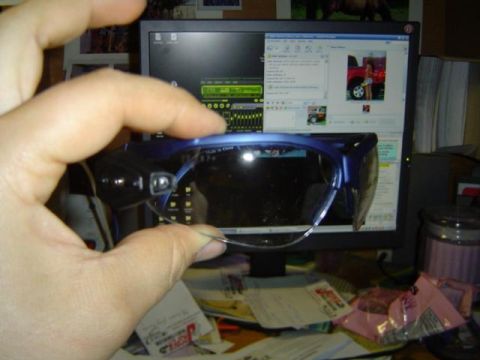 1979 Ford Bronco - A hand holds blue sunglasses in front of a computer screen that shows a red pickup truck.