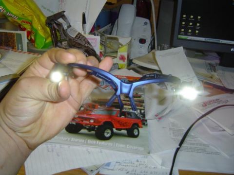 1979 Ford Bronco - A red 1979 Ford Bronco model is displayed on a magazine, held by a hand wearing magnifying glasses with lights.