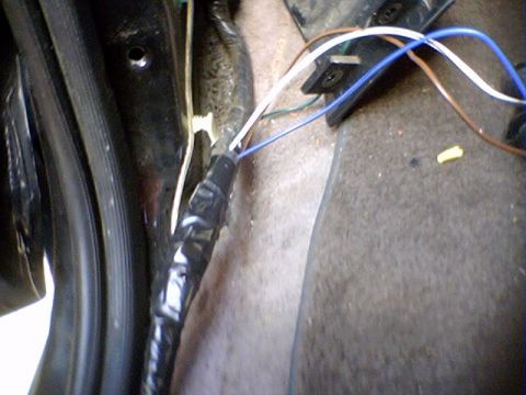 1994 Ford Bronco - A close-up view of a vehicle's interior wiring harness shows exposed wires and black tape.