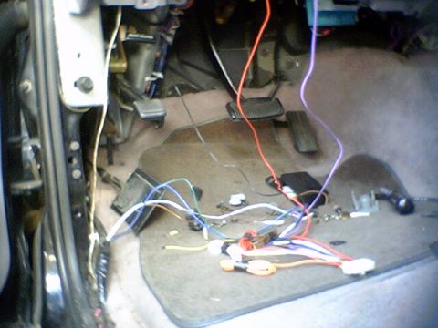1994 Ford Bronco - The interior of a vehicle shows a complex wiring harness with many exposed wires and connectors, suggesting aftermarket modifications or re…