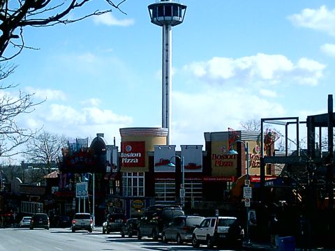 1997 Ford Escort - A street view shows an observation tower and several buildings, including Boston Pizza restaurants, with cars driving by.