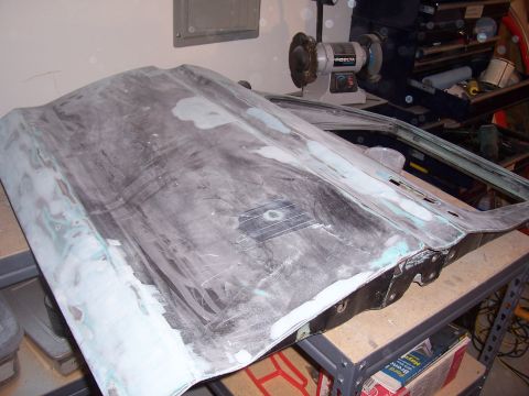 1978 Ford Bronco - A car door is undergoing bodywork, with primer and filler applied, resting on a workbench.