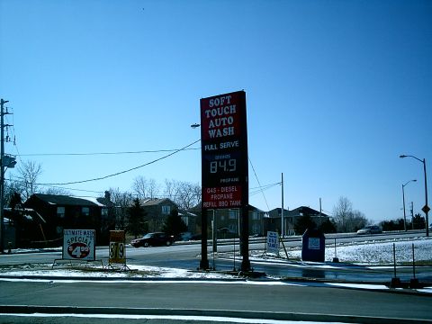 1997 Ford Escort - A dark sedan is visible near a gas station with a 'Soft Touch Auto Wash' sign.