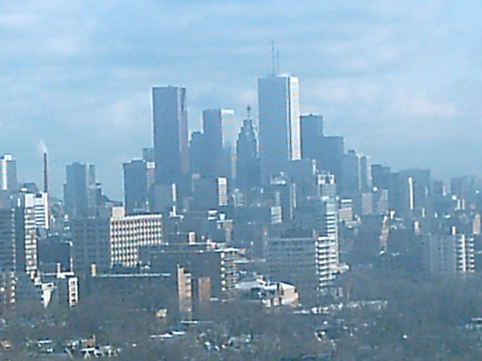 Cityscape with tall buildings under a hazy sky, with a watermark at the bottom right