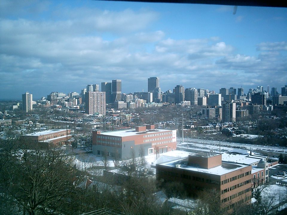 City buildings under a cloudy sky, with snow on the ground
