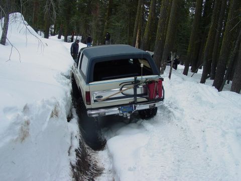 1986 Ford Bronco - Ford Bronco navigates a snowy path, with a shovel and gas can mounted on the rear.