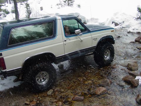 1986 Ford Bronco - This 1986 Ford Bronco navigates a rocky stream bed amidst a snowy landscape.