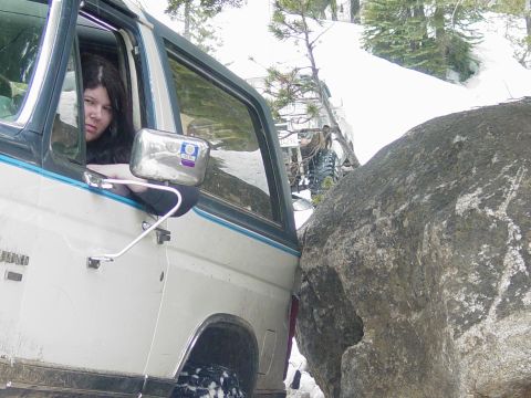 1986 Ford Bronco - The driver of a 1986 Ford Bronco peers out the window as the vehicle is wedged against a large boulder during an off-road excursion.