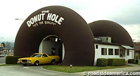 2002 Ford Crown Victoria - The Donut Hole drive-in features a unique donut-shaped architecture and a vintage yellow car.