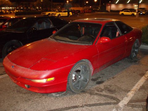 1997 Ford Probe - A red 1997 Ford Probe is parked in a lot at night, with other vehicles visible in the background.