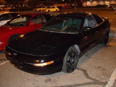 1997 Ford Probe - A black 1997 Ford Probe is parked in a lot at night, with other vehicles nearby.