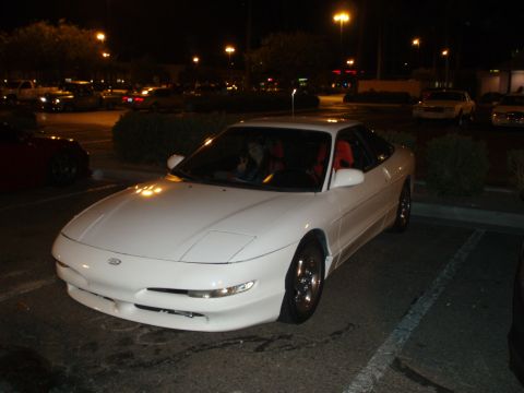 1997 Ford Probe - A white 1997 Ford Probe is seen parked at night, its distinctive pop-up headlights and coupe body style.