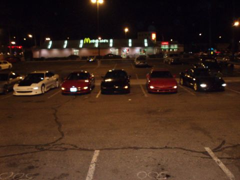 1997 Ford Probe - A group of cars are parked in a lot at night, illuminated by streetlights and the glow of a nearby McDonald's.