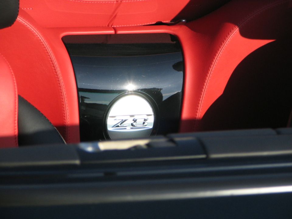Car interior with red leather seats and a circular Z8 badge on a black panel. Watermark reads SUPERMOTORS