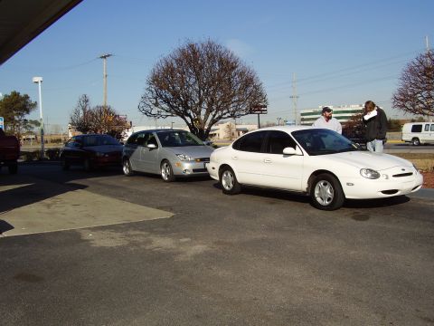 1997 Ford Taurus - A white 1997 Ford Taurus sedan is parked in a line of vehicles.