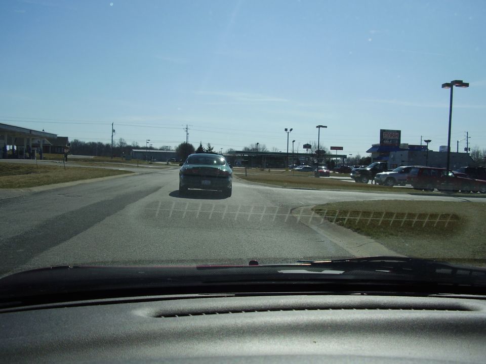 Green 1997 Ford Taurus from rear, driving on road