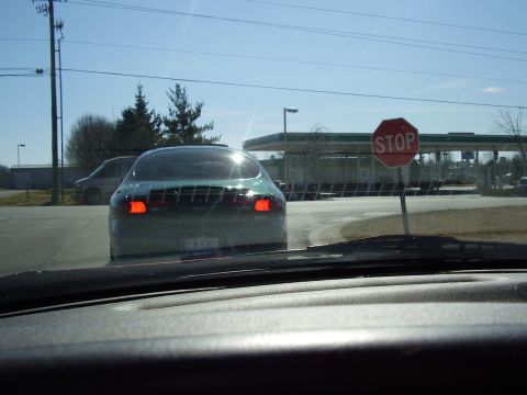 1997 Ford Taurus - Green sedan waits at a stop sign near a gas station, with another vehicle in the distance.