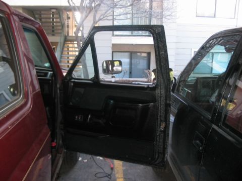 1991 Ford Bronco - Interior view of a maroon vehicle with its door ajar, parked next to a black vehicle.