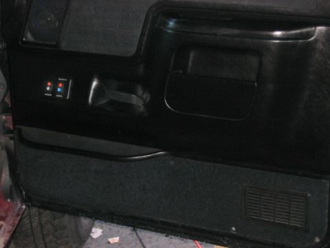 1991 Ford Bronco - Close-up of a car's interior door panel showing the handle and accessory switches.