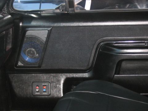 1991 Ford Bronco - Close-up of a vehicle's interior door panel, showing a speaker and window control buttons.