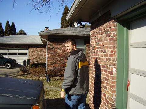 1997 Ford Taurus - Man stands in front of a house with a garage. A dark vehicle and a green truck are visible.