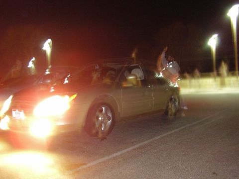 1997 Ford Taurus - Car with bright headlights on at night, showing occupants and streetlights.