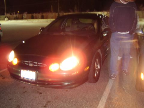 1997 Ford Taurus - A dark sedan is parked at night, its headlights illuminating the scene.