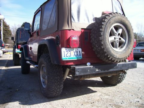 1998 Jeep TJ - Rear view of a red Jeep Wrangler, showing its spare tire and license plate. Another Jeep is visible.
