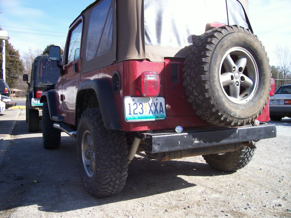 Red Jeep Wrangler with spare tire on back, Missouri license plate 123 XXA. Another Jeep is partially visible behind it
