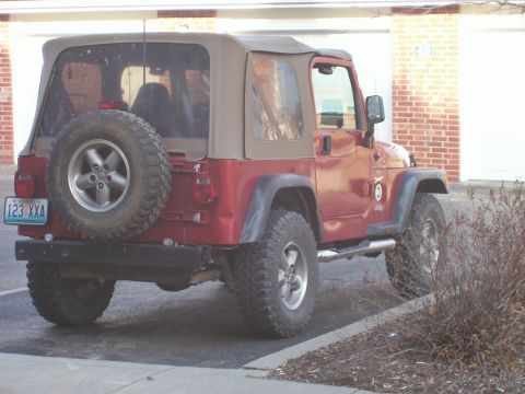 1998 Jeep TJ - This red Jeep Wrangler is viewed from the rear, showing its spare tire and soft top.