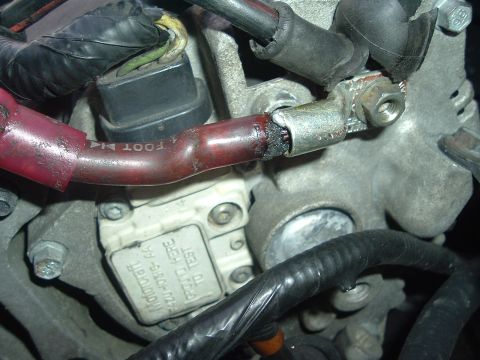 1993 Ford Taurus - Close-up of engine bay components including a red battery cable and a Motorcraft sensor.