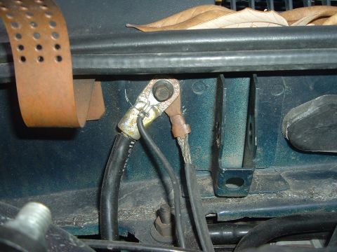 1993 Ford Taurus - Close-up view of vehicle battery terminals and cables, with some debris and leaves visible.