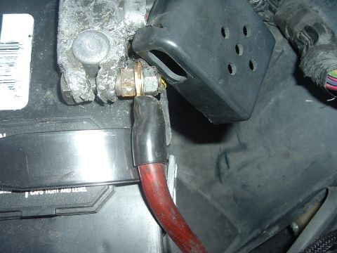 1993 Ford Taurus - Detail of a car battery terminal connection, showing corrosion and a red power cable.