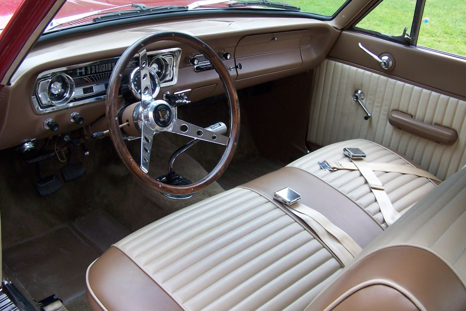 Classic car interior with wood steering wheel and tan/brown vinyl seats