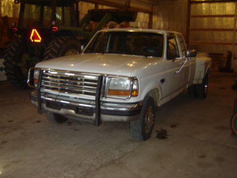 1992 Ford Bronco - This 1992 Ford Bronco dually pickup truck is shown in a garage with a tractor in the background.