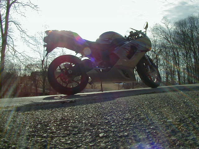 Side view of a tan motorcycle parked on a gravel road