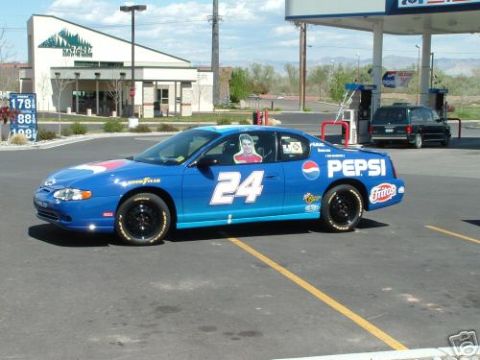 1978 Ford Mustang II - A blue race car with prominent Pepsi and Fritos branding is parked at a gas station, with another vehicle visible in the background.