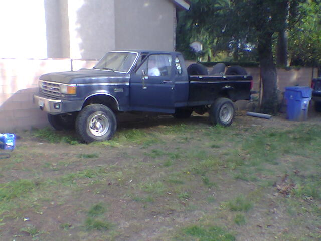 Dark blue 1987 Ford F-250 pickup truck parked on grass, front 3/4 view