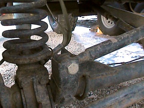 1977 Ford F-150 - Close-up view of the rear suspension components of a vehicle, showing the coil spring and axle.