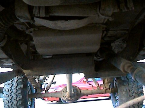 1977 Ford F-150 - The underside of a truck is shown, with a red vehicle in the background.