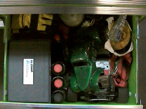 1977 Ford F-150 - A green toy car is stored in a toolbox drawer alongside other items.