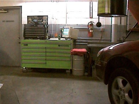 1977 Ford F-150 - Interior view of an auto repair shop showing a car's front fender and wheel.
