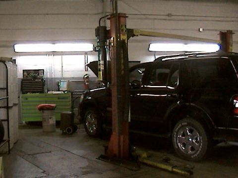 1977 Ford F-150 - A black SUV is positioned on a car lift inside a service bay.