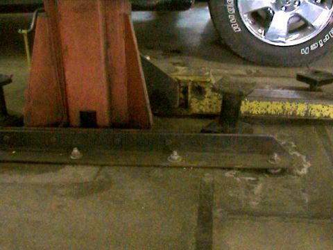 1977 Ford F-150 - A close-up view of a vehicle's wheel and tire, positioned on a lift in what appears to be a garage or service bay.