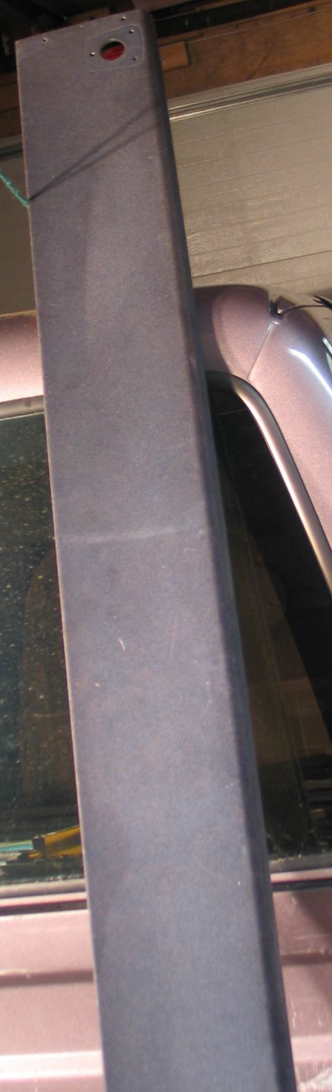 1994 Ford Bronco - A dark gray visor shelf is visible inside a vehicle, with a red light and mounting holes.