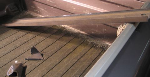 1994 Ford Bronco - Metal brackets and hardware are scattered on the wooden floor of a truck bed.
