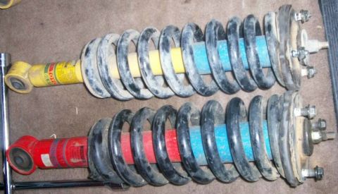 1993 Ford Bronco - Pair of coilover shock absorbers with springs. One is yellow, the other is red.
