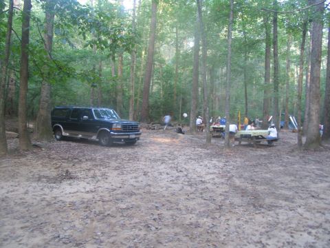 1995 Ford C-150 (Centurion Conversions) - Campsite scene with a 1995 Ford C-150 (Centurion Conversions) and people gathered at picnic tables.