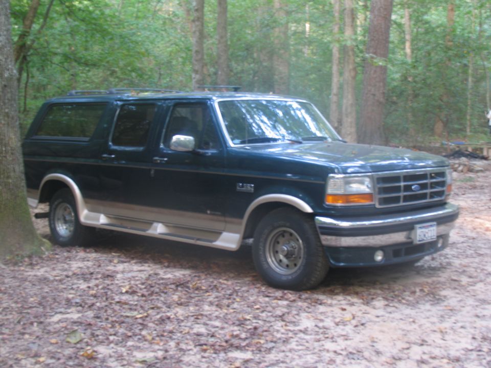1995 Ford C-150 Centurion Conversions SUV, dark green with tan trim, parked in woods