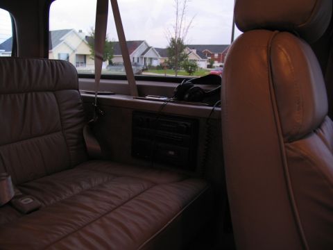 1995 Ford C-150 (Centurion Conversions) - View from the passenger seat of a van, looking out the window at houses on a cloudy day.